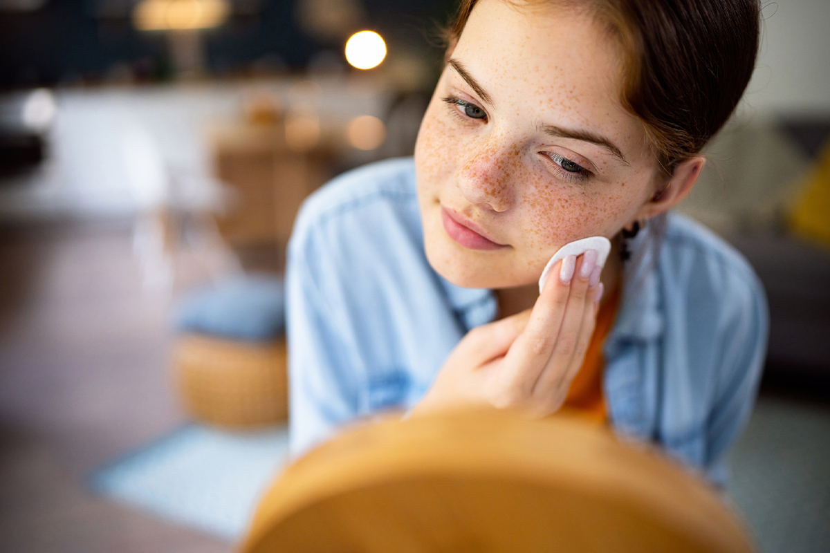 a young girl cleaning her face and looking in a mirror after getting acne treatment in Sarasota